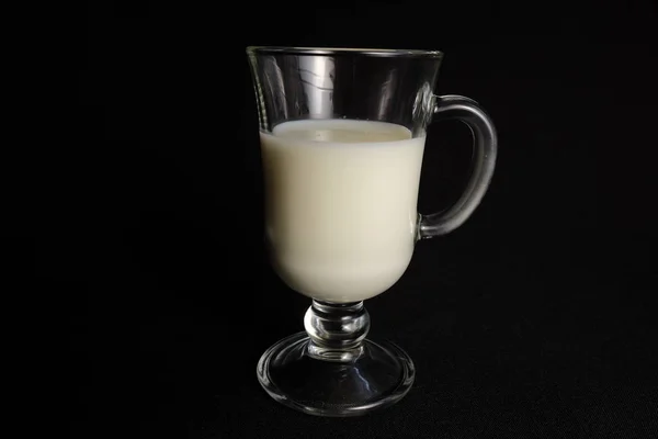 Glass of milk in transparent glass on black background