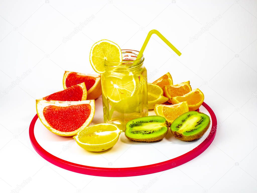 Sliced citrus fruits and lemonade in glass jar on white background
