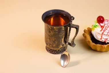 Lezzetli tatlı çörek ve çay bej renkli arka plan üzerinde vintage metal Kupası