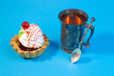 Lezzetli tatlı çörek ve çay mavi arka plan üzerinde vintage metal Kupası