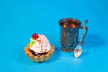 Lezzetli tatlı çörek ve çay mavi arka plan üzerinde vintage metal Kupası