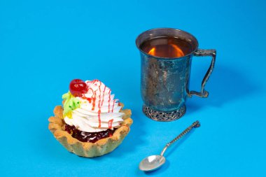 Lezzetli tatlı çörek ve çay mavi arka plan üzerinde vintage metal Kupası