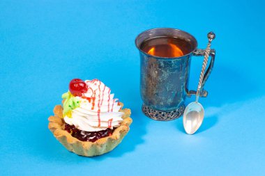 Lezzetli tatlı çörek ve çay mavi arka plan üzerinde vintage metal Kupası