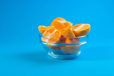 mavi bir arka plan üzerinde cam kapta sulu lezzetli mandalina