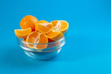 mavi bir arka plan üzerinde cam kapta sulu lezzetli mandalina