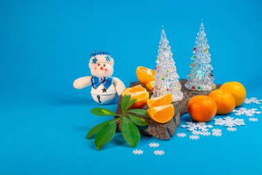 sulu ve lezzetli mandalina ve oyuncak Noel ağaçları mavi zemin üzerine