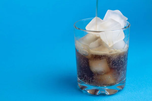 black carbonated drink with ice cubes