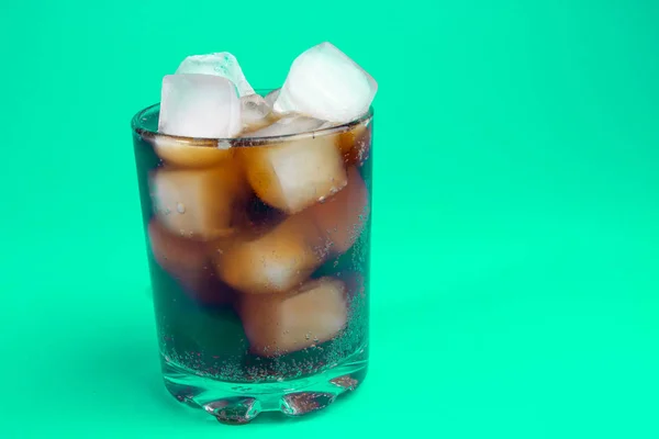 black carbonated drink with ice in a glass