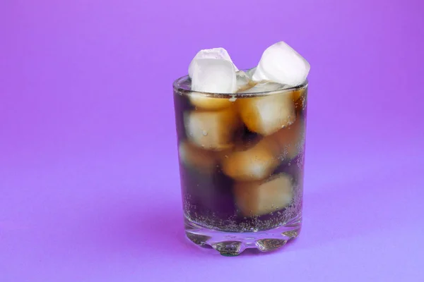 black carbonated drink with ice in a glass