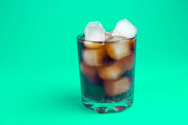 black carbonated drink with ice in a glass