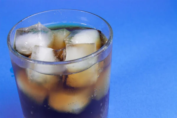 black carbonated drink with ice in a glass