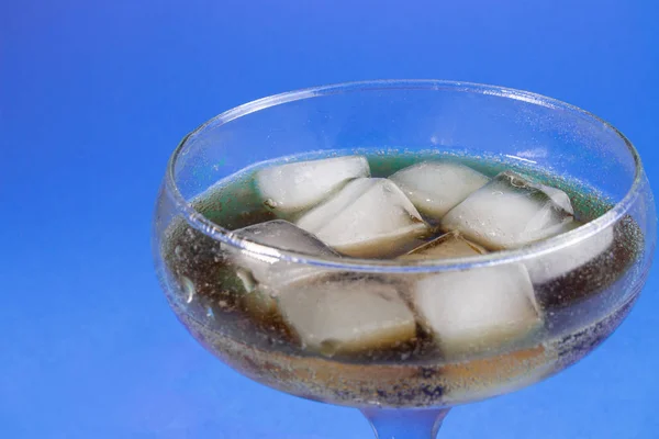 black carbonated drink with ice in a glass