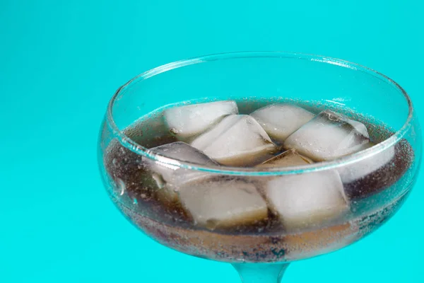 black carbonated drink with ice in a glass