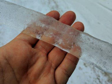 El, bir elinde şeffaf buz parçası büyük buz saçağı