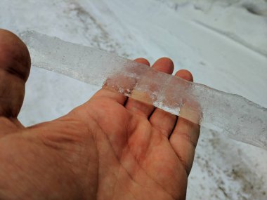 El, bir elinde şeffaf buz parçası büyük buz saçağı