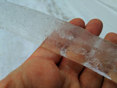 El, bir elinde şeffaf buz parçası büyük buz saçağı