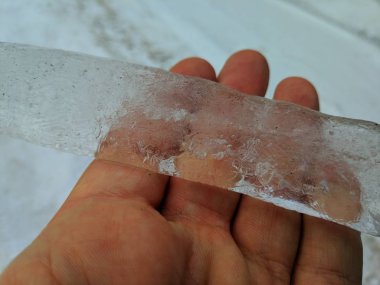 El, bir elinde şeffaf buz parçası büyük buz saçağı