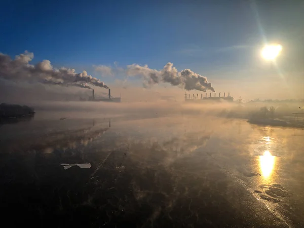 winter landscape river with ice, smoke from the pipes of the plant, river port in winter