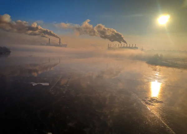 winter landscape river with ice, smoke from the pipes of the plant, river port in winter