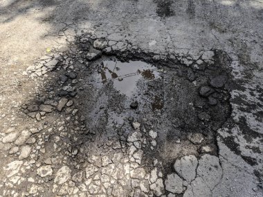 çok kötü asfalt yol. yolda derin çukurlar. kötü onarım. çatlak asfalt