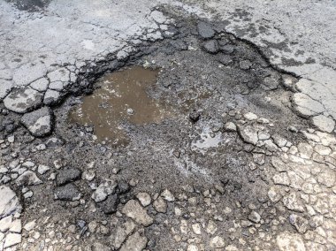 çok kötü asfalt yol. yolda derin çukurlar. kötü onarım. çatlak asfalt