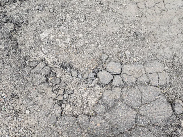 very bad asphalt road. deep pits on the road. bad repair. cracked asphalt