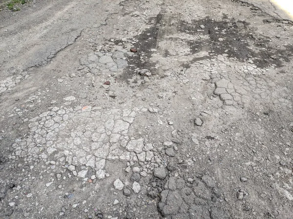 very bad asphalt road. deep pits on the road. bad repair. cracked asphalt