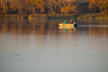 Teknedeki balıkçılar. Sonbaharda gölde bir tekne. Güzel bir sonbahar manzarası ve denizde bir tekne..