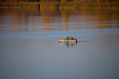 Teknedeki balıkçılar. Sonbaharda gölde bir tekne. Güzel bir sonbahar manzarası ve denizde bir tekne..