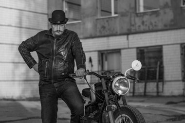 Bir motorcunun siyah beyaz fotoğrafı. Güzel bir adamın bıyığı. Şapkalı adam. Motosikletli vahşi adam