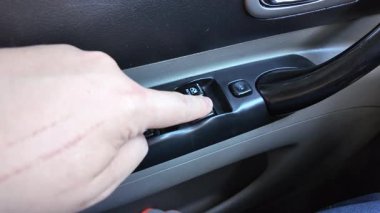 Analog pencere kaldırma düğmeleri. Adam arabanın camını açıyor. Arabadaki eski düğmeler. Adam pencereyi açma düğmesine basıyor. Pencere kaldırıcı. Bir araba düğmesindeki pencere kaldırıcıları