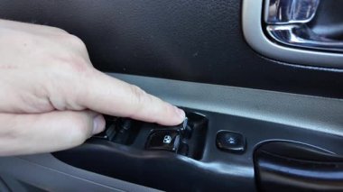 Analog pencere kaldırma düğmeleri. Adam arabanın camını açıyor. Arabadaki eski düğmeler. Adam pencereyi açma düğmesine basıyor. Pencere kaldırıcı. Bir araba düğmesindeki pencere kaldırıcıları
