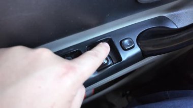 Analog pencere kaldırma düğmeleri. Adam arabanın camını açıyor. Arabadaki eski düğmeler. Adam pencereyi açma düğmesine basıyor. Pencere kaldırıcı. Bir araba düğmesindeki pencere kaldırıcıları