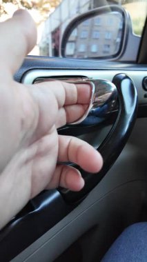 El ile arabanın kapısını açan genç adam. Bir yolcu mavi bir arabanın kapısını açar, arka koltuğa oturur ve kapıyı kapatır.,