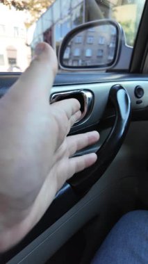 El ile arabanın kapısını açan genç adam. Bir yolcu mavi bir arabanın kapısını açar, arka koltuğa oturur ve kapıyı kapatır.,