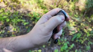 In a man's hand the alarm key fob, when the button is pressed, a red LED lights up, signaling that the protected object has been alarmed. Closeup.