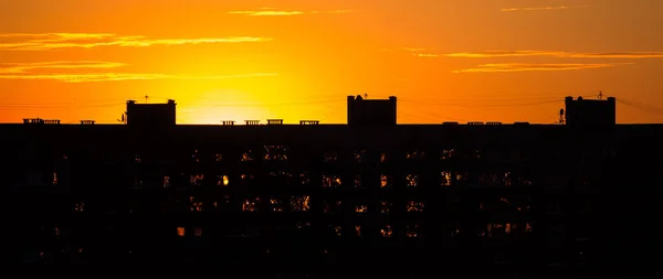Günbatımı gökyüzünün arka planında yüksek bir binanın silüeti..