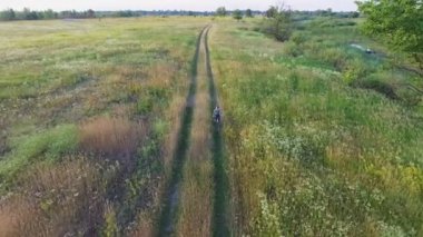 Çocuk binicilik bisiklet havadan görüntüleri. Kırsal yol. Yaz tarım alanında. Ukraynalı doğa