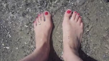 Açık deniz suyu sahilde kadın ayaklarda closeup. Ayak parmakları güzel kırmızı pedikür ile. ağır çekim