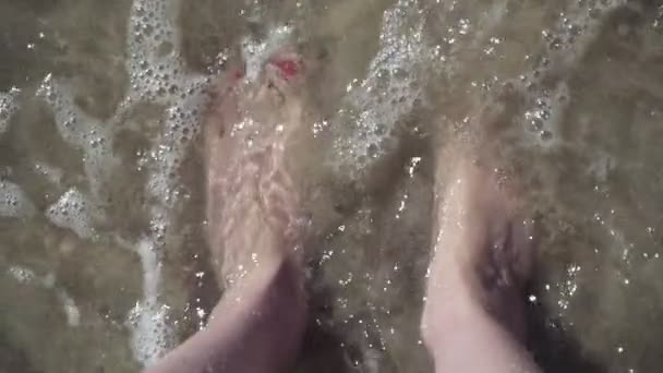 Closeup de pés femininos em água do mar clara na praia. Dedos dos pés com pedicure vermelho bonito. câmara lenta — Vídeo de Stock