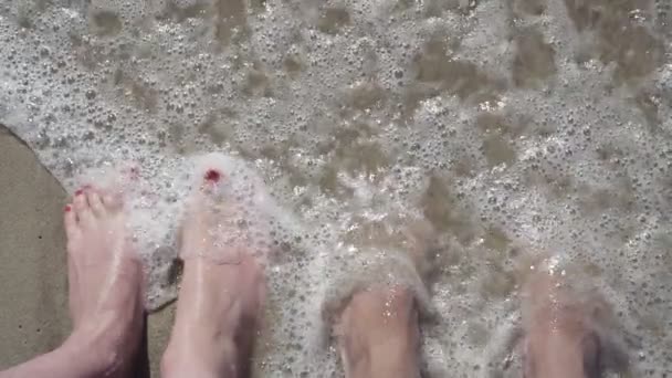 Piernas de hombre y chica en el océano. vídeo en cámara lenta — Vídeo de stock