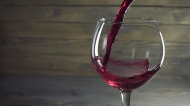 Bardağa ahşap zemine kırmızı şarap dökerek. Yavaş çekim