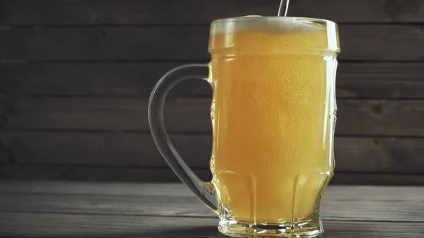 ビールのジョッキに注ぐビールのスローモーション撮影。木製の背景を — ストック動画