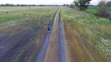 Havadan görüntüleri kırsal yol boyunca çalışan çocuk. Yaz tarım alanında. Ukraynalı doğa