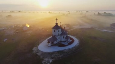 Havadan görüntüleri video Sisli sabah kilisede küçük bir köy. Gündoğumu zaman. Kiev region, Ukrayna. Uçan Desna Nehri