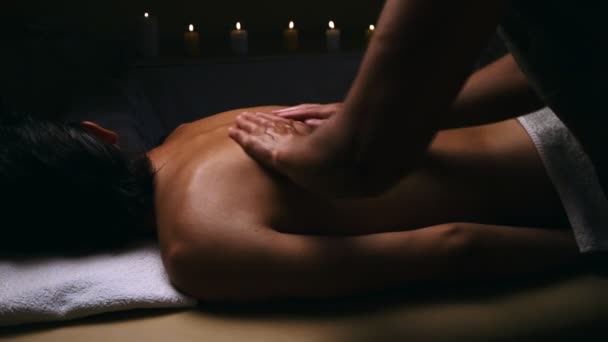 Receiving Body Massage at Spa Club. Hands massaging the back. Evening light. — Stock Video