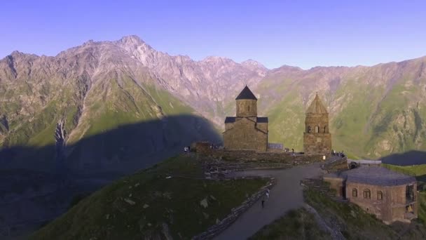 Légifelvételek. A Gergeti templom, a háttérben a Kazbek — Stock videók