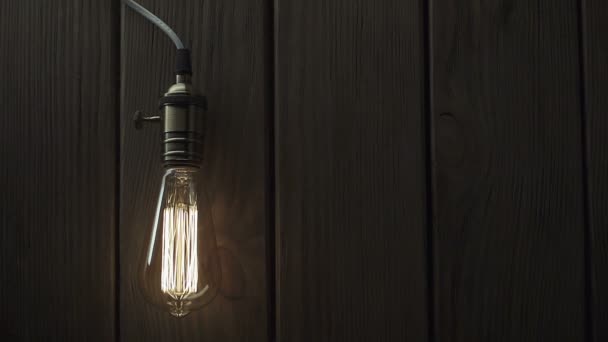 Light bulb illuminates on wooden background — Stock Video