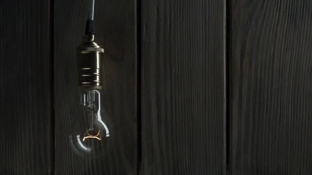 A lâmpada acende-se lentamente, rapidamente treme em um contexto de uma madeira — Vídeo de Stock