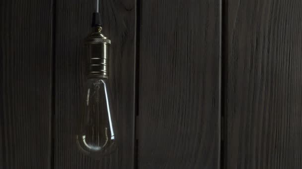 Bombilla se ilumina sobre fondo de madera — Vídeos de Stock